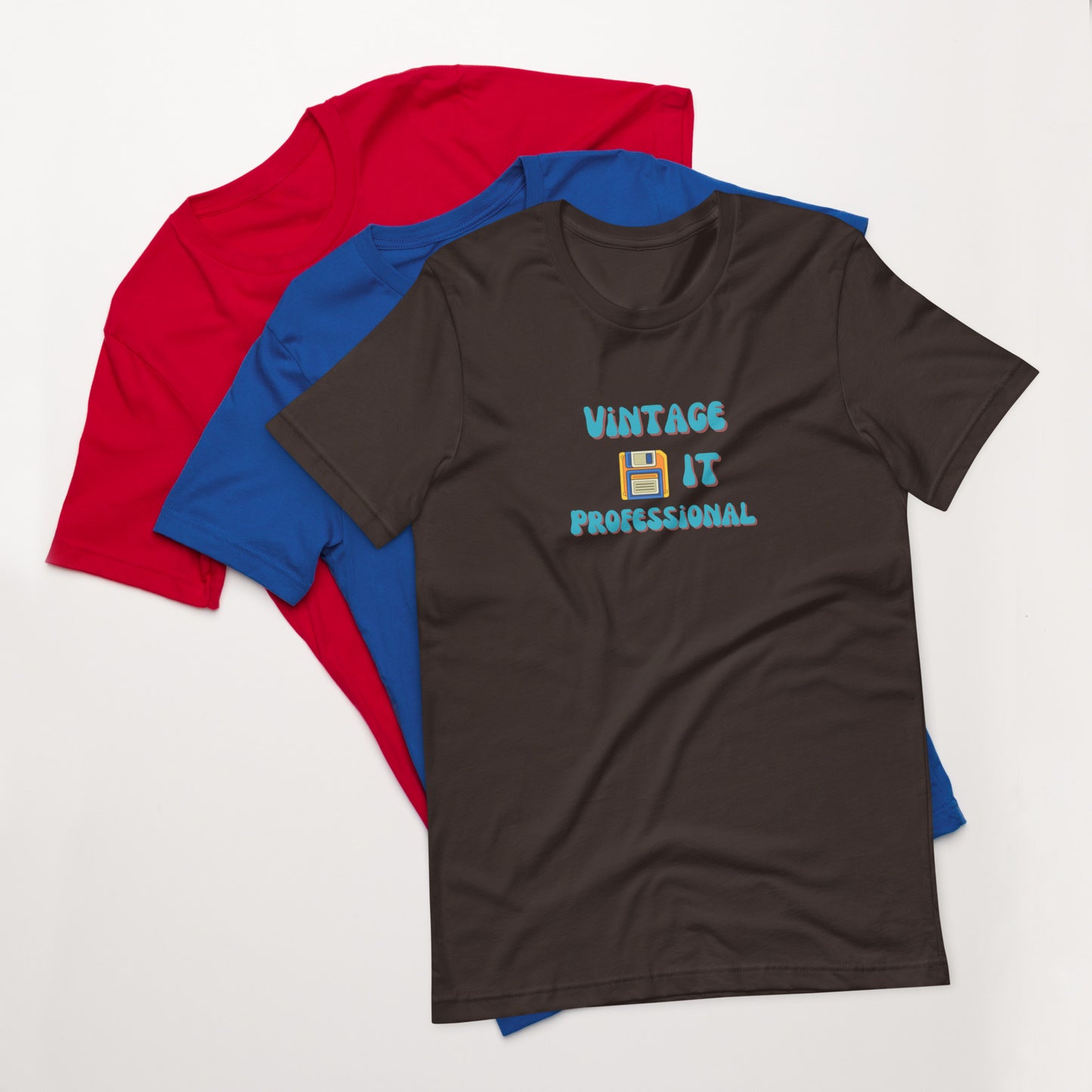 A stack of t-shirts with a brown one on top that says Vintage IT Professional and has a picture of a diskette on it.