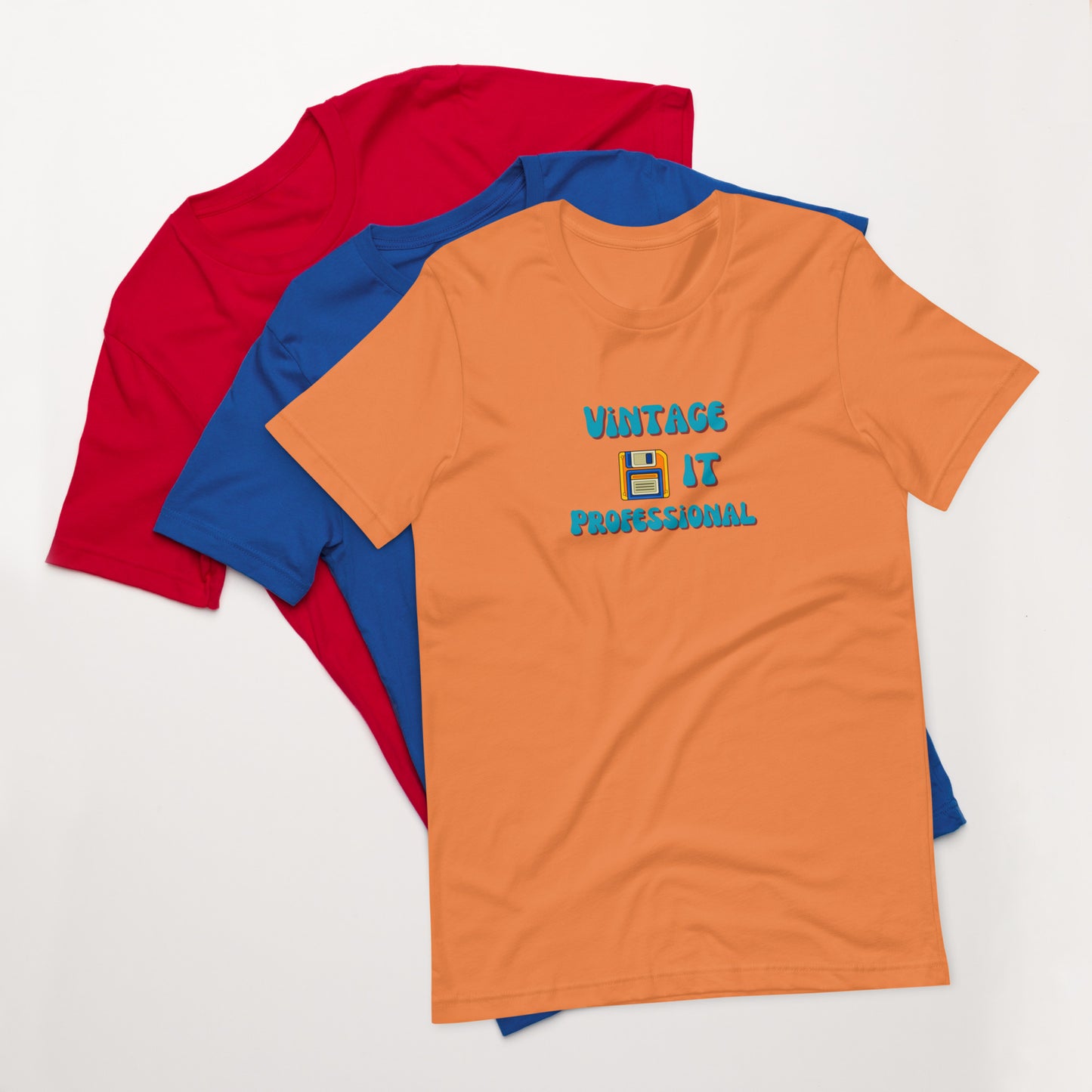 A stack of t-shirts with an orange one on top that says Vintage IT Professional and has a picture of a diskette on it.