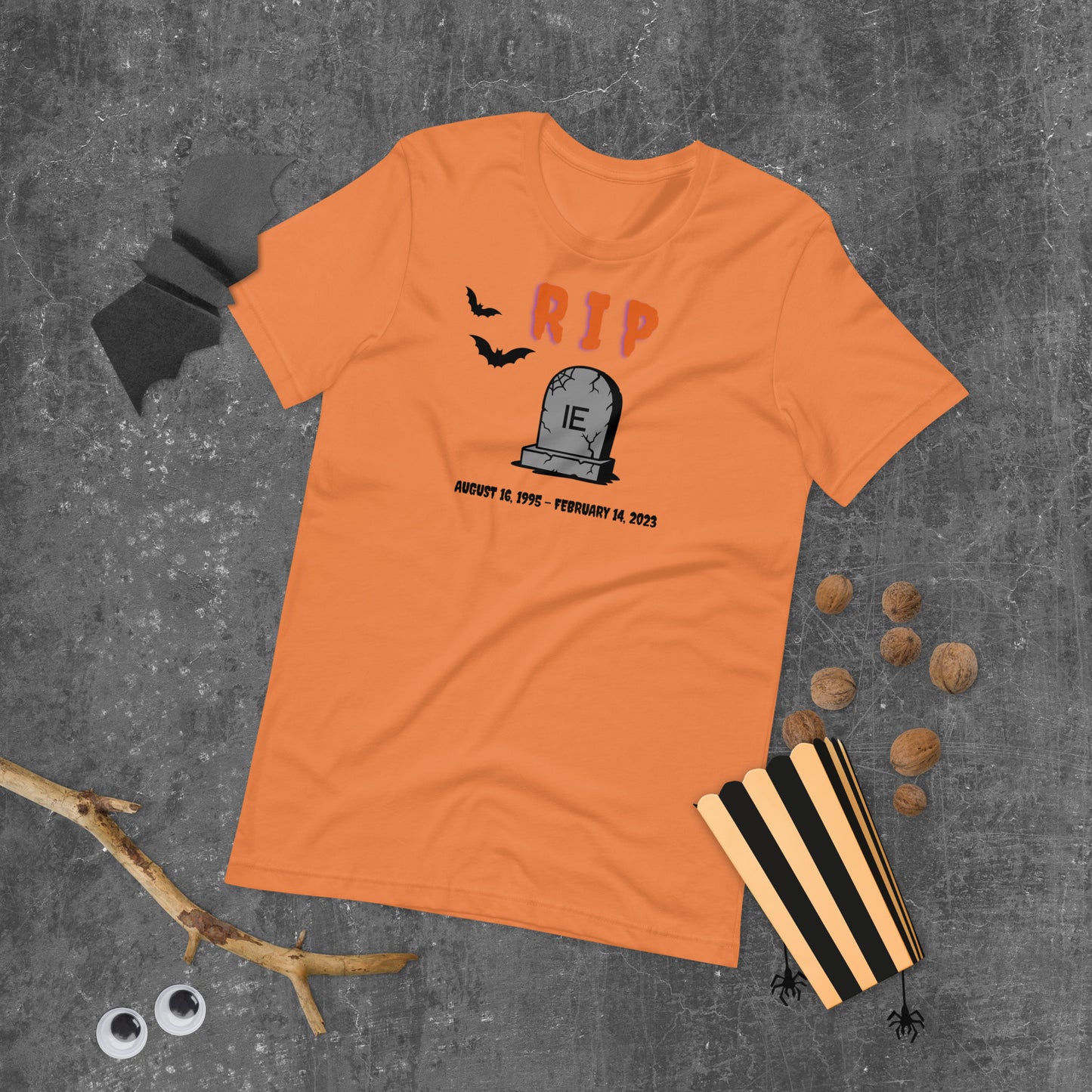 A Halloween T-Shirt for Sysadmins that shows a picture of a tombstone with the letters IE on it and the title RIP and the date Internet Explorer premiered and the date that it was disabled.