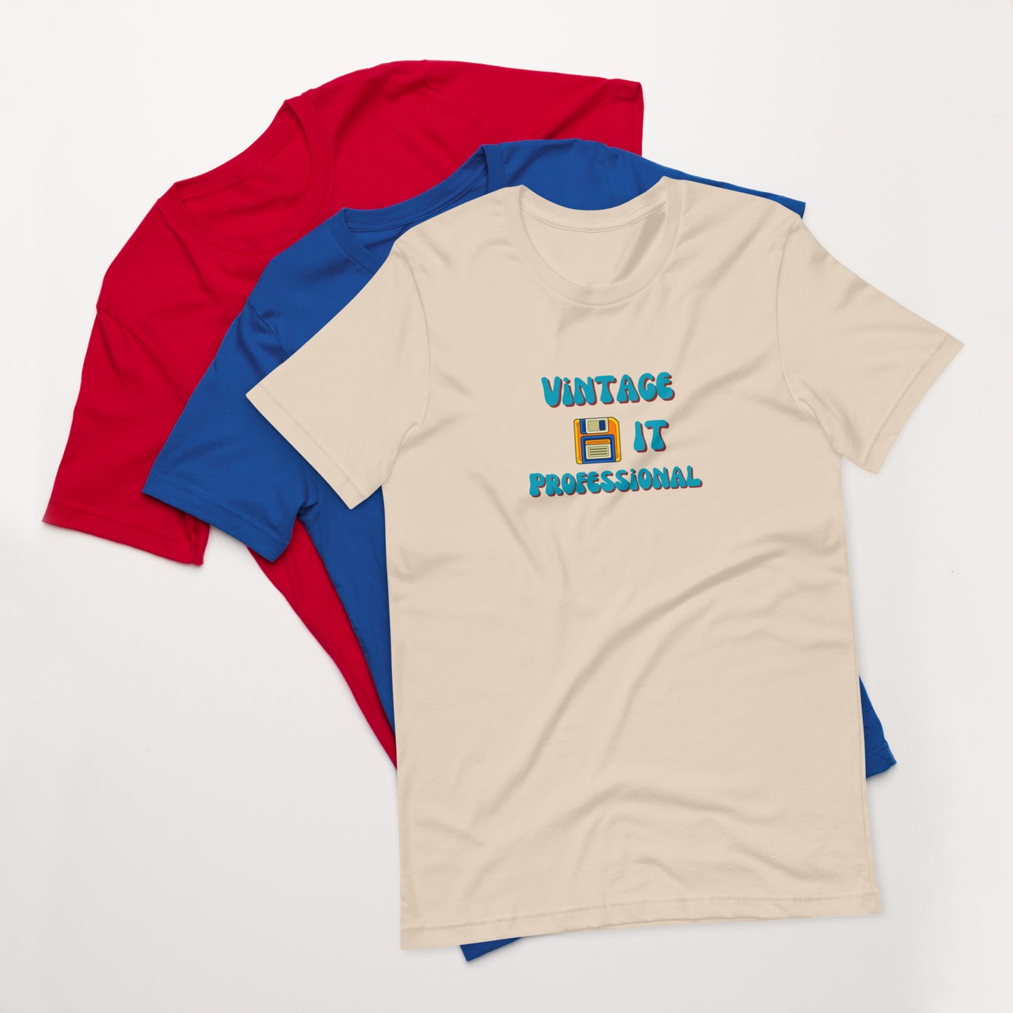 A stack of t-shirts with a soft cream one on top that says Vintage IT Professional and has a picture of a diskette on it.