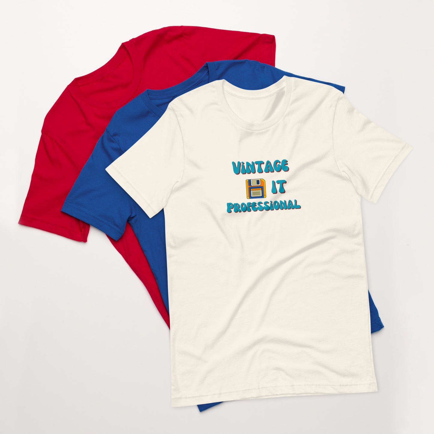 A stack of t-shirts with a vintage white one on top that says Vintage IT Professional and has a picture of a diskette on it.
