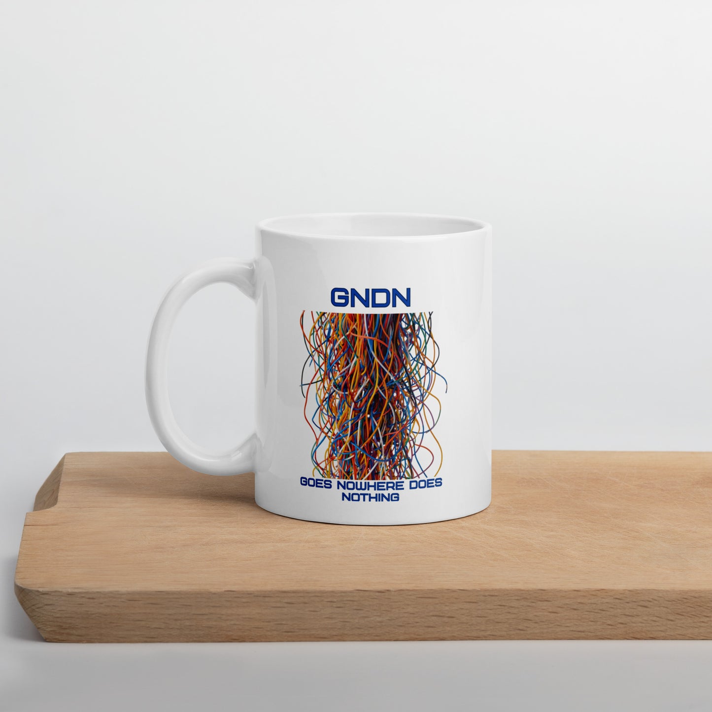 A white mug with a bunch of colorful ethernet cables that go no where and the words GNDN:  Goes Nowhere Does Nothing